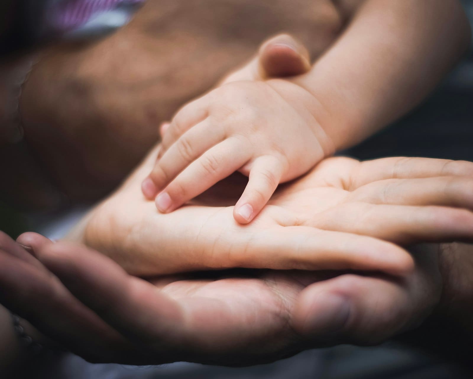 A baby's hand resting on a parent's palm